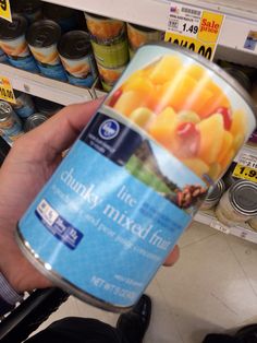 a person holding up a can of fruit drink