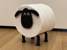 a sheep made out of toilet paper sitting on top of a wooden floor next to a wall