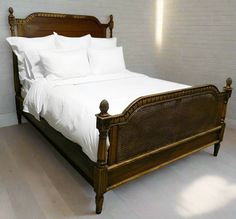 a bed with white sheets and pillows on top of it in a room that has wood floors