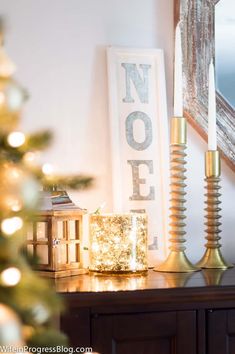 a wooden table topped with a christmas tree next to a candle holder and framed sign