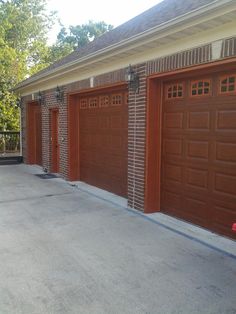 three brown garage doors in front of a brick building