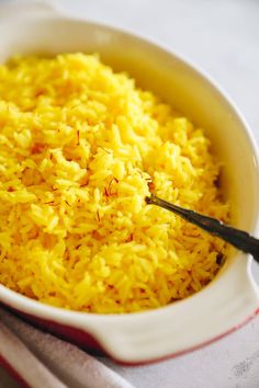 a white bowl filled with yellow rice on top of a table