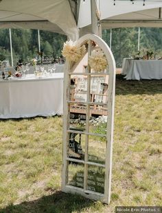 an old window is used as a mirror for a wedding reception at a tented venue