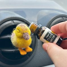 a small yellow bird sitting on top of a car dashboard next to an orange bottle