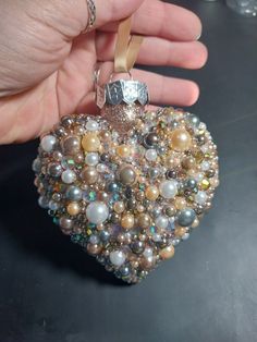 someone holding a heart shaped ornament in their hand