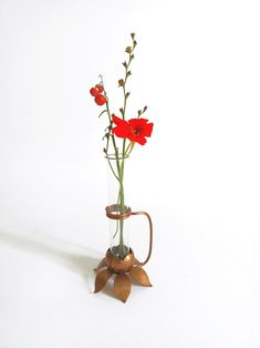 a vase filled with red flowers on top of a white table next to a watering can