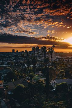 the sun is setting over a city with palm trees