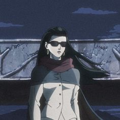 a woman wearing sunglasses and a cape standing in front of snow covered ground at night