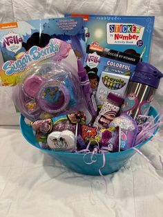 a blue basket filled with toys on top of a bed