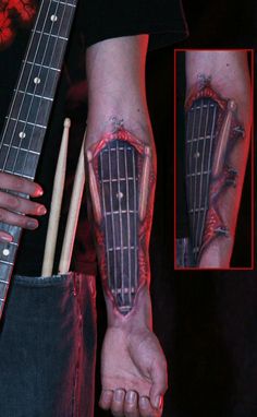 a man with tattoos on his arm holding a guitar