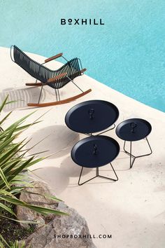 A black outdoor rocking chair with bamboo armrest and three black round tray tables in different sizes placed beside the pool Outdoor Rocking Chair, Outdoor Rocking Chairs, Home Improvement Store, Outdoor Oasis