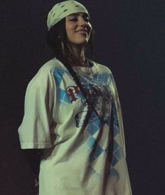 a woman standing in front of a black background wearing a white shirt and bandana