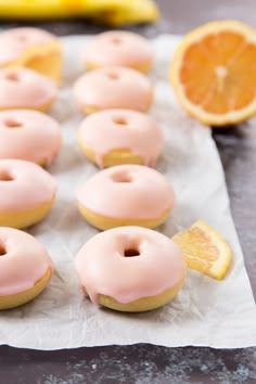 doughnuts with pink icing and orange slices on a piece of parchment paper