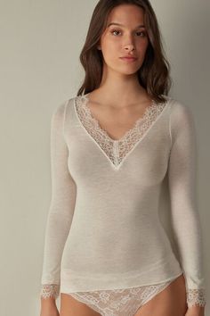 Long-sleeved modal cashmere ultralight shirt enhanced with lace. Elegant Fine Knit Tops For Layering, Elegant White Fine Knit Top, Elegant Delicate Lace Top For Fall, Elegant Long Sleeve Tops For Layering, Elegant Long Sleeve Top With Lace Sleeves, Elegant Tops With Lace Trim For Fall, Elegant Spring Tops With Delicate Lace, Elegant Lace Tops For Fall, Elegant Lace Trim Tops For Fall