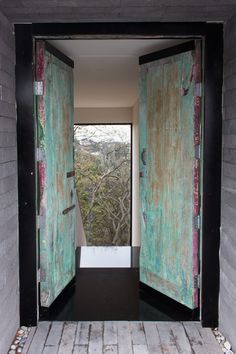 an open door leading into a room with wood floors and green paint on the doors