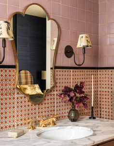 a bathroom with pink tiles and gold fixtures on the wall, along with a marble counter top