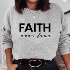 Keep warm and comfortable in this Faith Over Fear Sweatshirt. This cool Christian sweatshirt is soft, stylish, and sure to keep you warm in the colder months. It's versatile to wear for a day outdoors, heading to the gym, or a lazy day watching movies on the couch. Wearing Christian hoodies and sweatshirts can be a subtle way to express your faith and create conversations with anyone and be a gentle reminder to encourage you in any season. They can also spread encouraging words of faith everywhe Comfortable Black Winter Tops, Fall Slogan Tops For Leisure, Slogan Tops For Leisure In Fall, Gray Winter Loungewear T-shirt, Winter Leisure Sweater With Letter Print, Leisure Winter Sweater With Letter Print, Gray Letter Print T-shirt For Winter, Winter Gray Letter Print T-shirt, Casual Fleece T-shirt For Fall