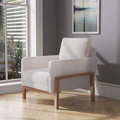 a white chair sitting on top of a hard wood floor next to a large window