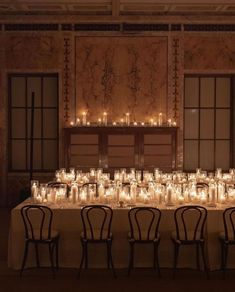 a long table with many lit candles on it and chairs in front of the table