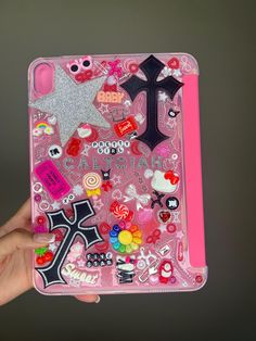 someone holding up a pink case with many different things on it