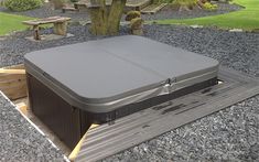 a hot tub sitting on top of a wooden platform next to a tree and rocks