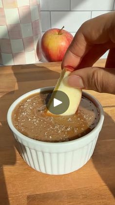 a person dipping an apple into a bowl