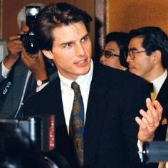 a man in a suit and tie is surrounded by reporters