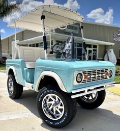 a light blue truck parked in front of a building with a golf cart attached to it