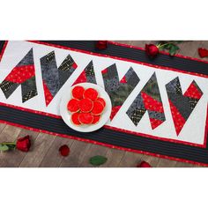 a table runner with red roses on it and a plate of cookies next to it