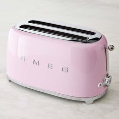 a pink toaster with the word smeg on it sitting on a counter top