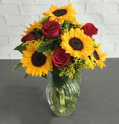 a vase filled with red roses and yellow sunflowers on top of a table