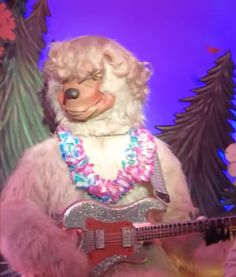 a stuffed animal with a guitar in front of a christmas tree and decorations on the wall