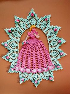 a crocheted doily with a pink dress on it