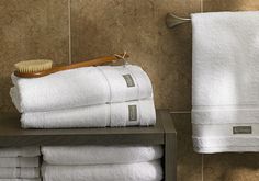 a stack of white towels sitting on top of a shelf next to a wooden brush