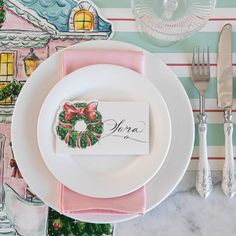 a place setting with pink napkins, silverware and a christmas ornament