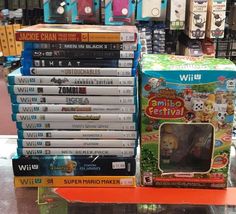 a pile of nintendo wii games sitting on top of a display case in a store