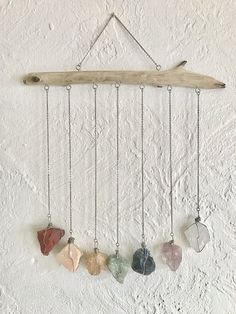 five stone pendulums hanging from a wooden branch on a white wall with snow in the background