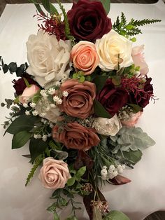 a bouquet of flowers sitting on top of a white cloth covered table with greenery