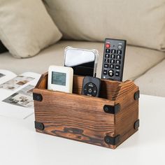 a wooden box with remotes in it sitting on a table next to a couch