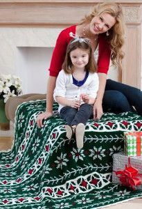 a woman and her daughter sitting on a christmas blanket