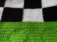 a crocheted blanket with black, white and green squares