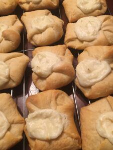 several rolls with white icing sitting on a cooling rack