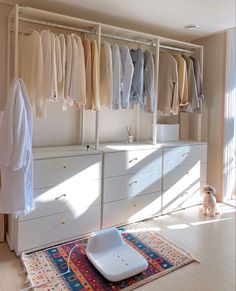 an organized closet with white drawers and clothes on hangers