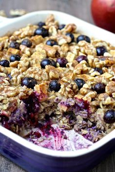 a blueberry baked oatmeal in a white dish next to an apple