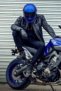 a man sitting on the back of a motorcycle wearing a blue helmet and black gloves