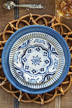 a blue and white plate sitting on top of a woven place mat next to a glass