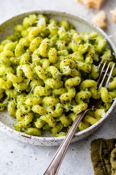 a white bowl filled with green pasta covered in pesto