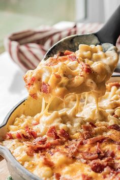 a spoon full of macaroni and cheese being lifted from a casserole dish