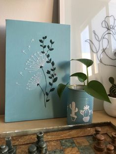 a plant is sitting on a table next to a potted plant and a painting