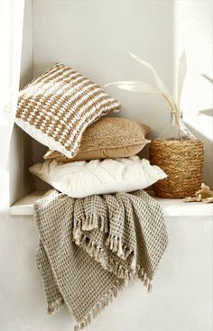 pillows and blankets stacked on top of each other in a corner next to a basket